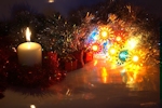 Kerstkaart: Witte brandende kaars met gekleurde kerstverlichting en kerstslingers