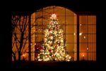 Kerstkaart: Rijkelijk verlichte kerstboom achter het raam