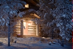 Kerstkaart: Verlichte voorkant van het huis met besneeuwde sparren