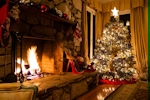 Kerstkaart: Rijk versierde en verlichte kerstboom staat naast de brandende open haard
