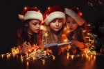 Kerstkaart: Meisjes met kerstmutsen spelen met de kerstverlichting terwijl ze een boek lezen