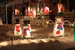 Kerstkaart: Verlichte sneeuwpoppen en andere beelden staan in een besneeuwde tuin