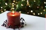 Kerstkaart: Roodbruine brandende kaars op een witte tafel