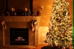 Kerstkaart: Verlichte kerstboom naast een brandende witte open haard met kerstsokken aan de schouw