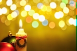 Kerstkaart: Gele brandende kaars met een groene en een rode kerstbal