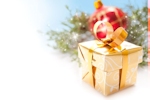 Kerstkaart: Goudkleurig pakje met op de achtergrond een rode kerstbal